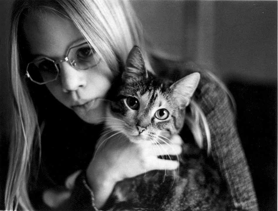 Young woman holding her cat: The cat is looking at the camera while the girl looks away from the camera.